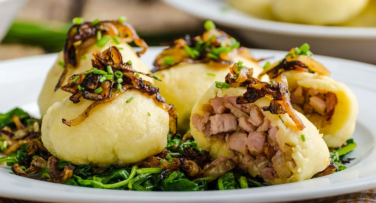 Kartoffelknödel aus Tschechien, mit Fleisch gefüllt und mit gebratenen Zwiebeln oben drauf serviert.
