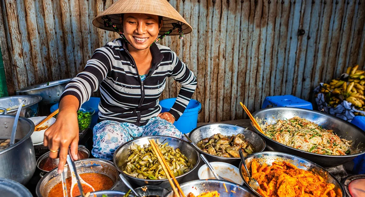 Köchin bereitet vietnamesisches Street Food an einem Marktstand in Vietnam zu