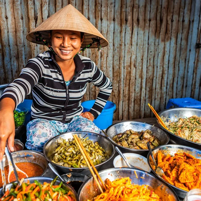 Köchin bereitet vietnamesisches Street Food an einem Marktstand in Vietnam zu