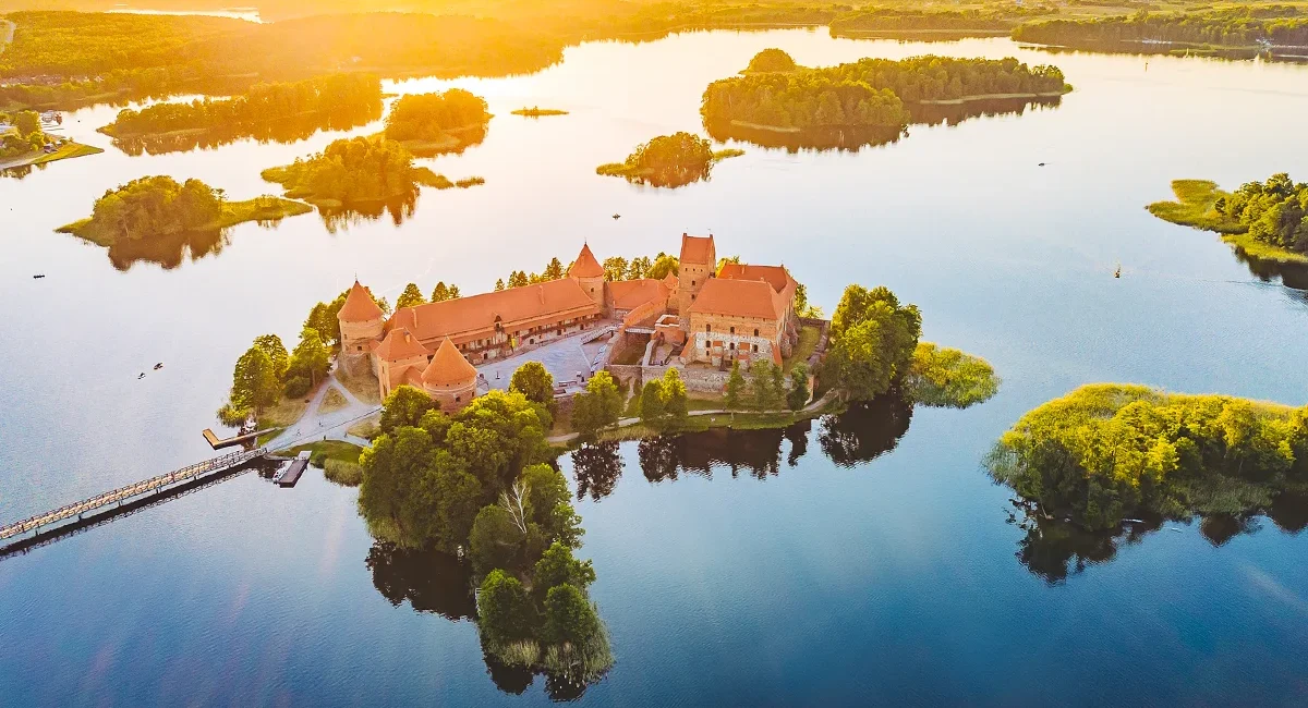Das mittelalterliche, aus rotem Backstein erbaute Wasserschloss Trakai, das bei Sonnenuntergang malerisch im ruhigen, inselreichen Galvė-See in Litauen liegt.