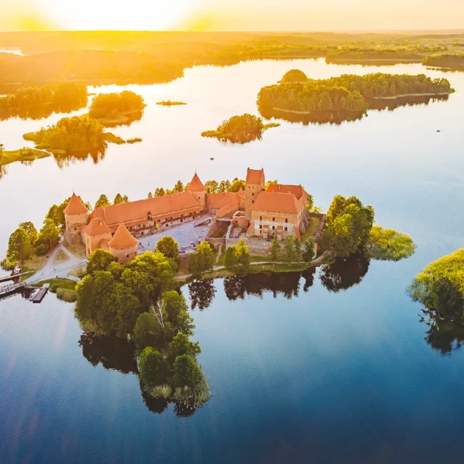 Das mittelalterliche, aus rotem Backstein erbaute Wasserschloss Trakai, das bei Sonnenuntergang malerisch im ruhigen, inselreichen Galvė-See in Litauen liegt.