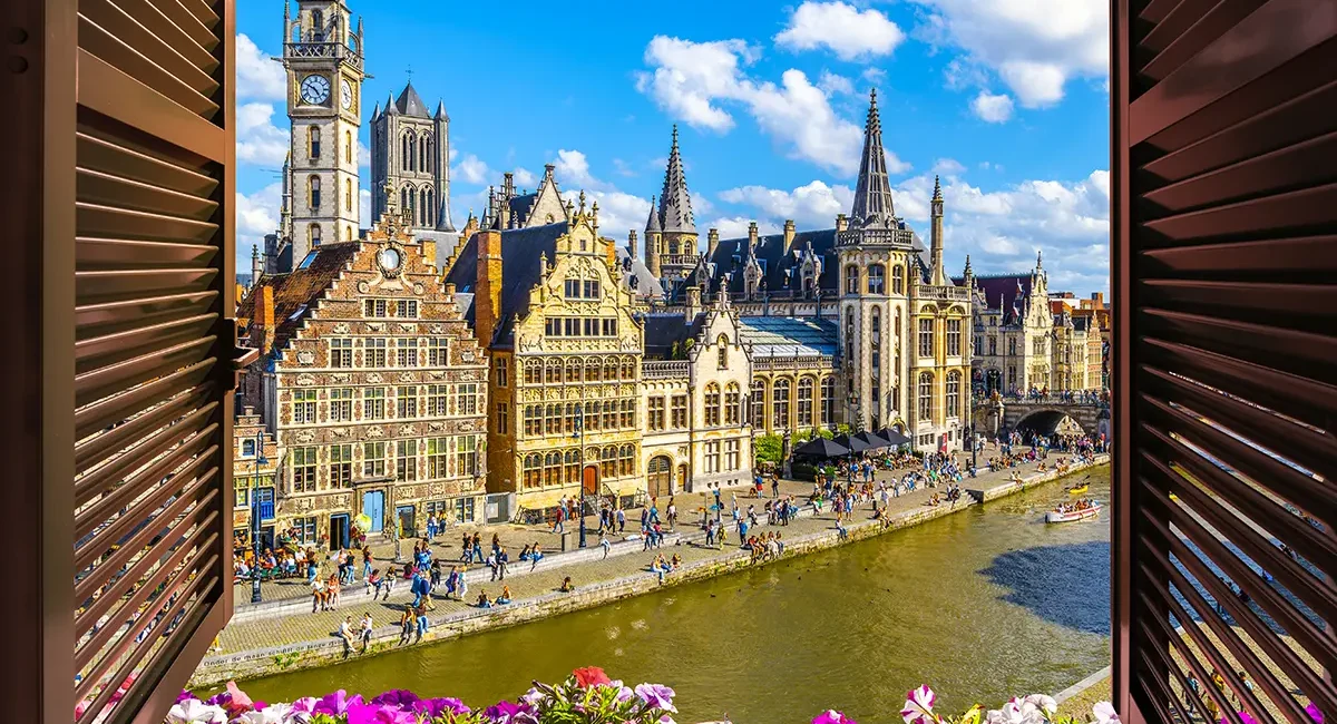 Blick aus einem Fenster in Gent auf einen Kanal und hübsche historische Gebäude.