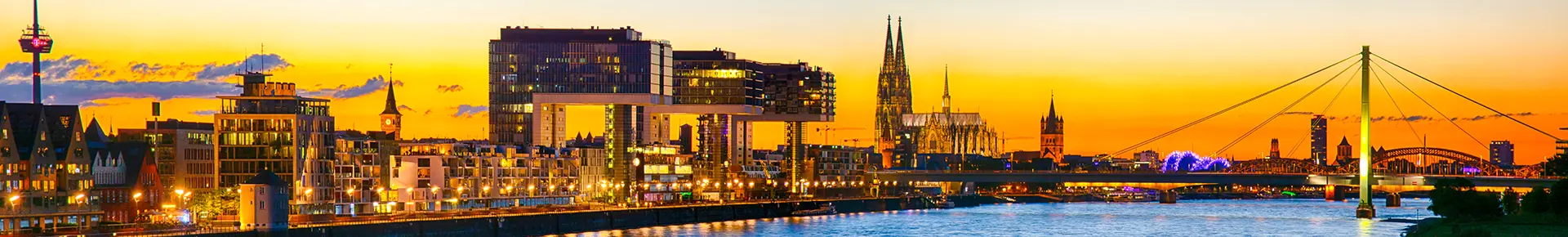 Blick auf den Rhein in Köln bei Sonnenuntergang mit dem Dom, dem Medienhafen und der Skyline der Stadt.