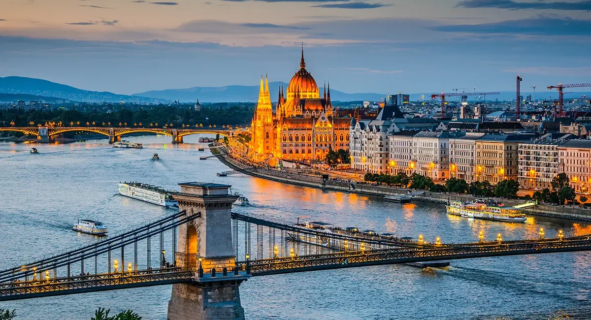 Budapest in der Abendstimmung mit beleuchteten Brücken über der Donau und dem hell erleuchteten Parlament.