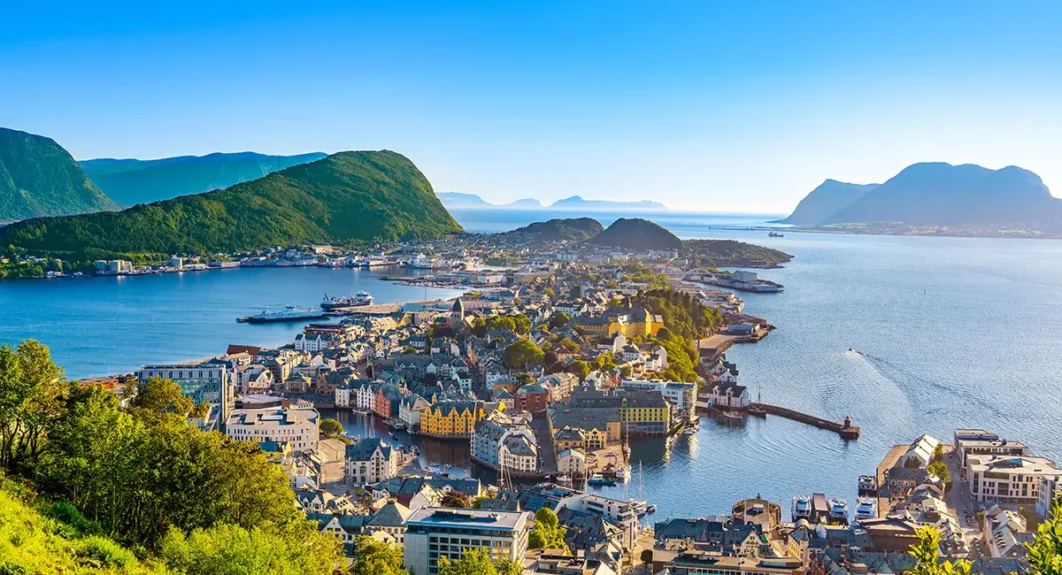 Blick von oben auf Ålesund in Norwegen mit bunten Häusern, Hafen und umliegenden Inseln.