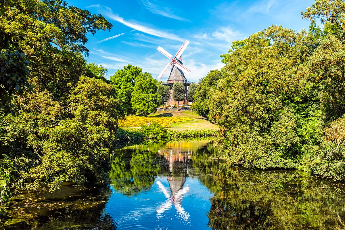 Die historische Mühle am Wall in Bremen, die sich idyllisch in den herbstlichen Wallanlagen am Ufer des Wallgrabens spiegelt.