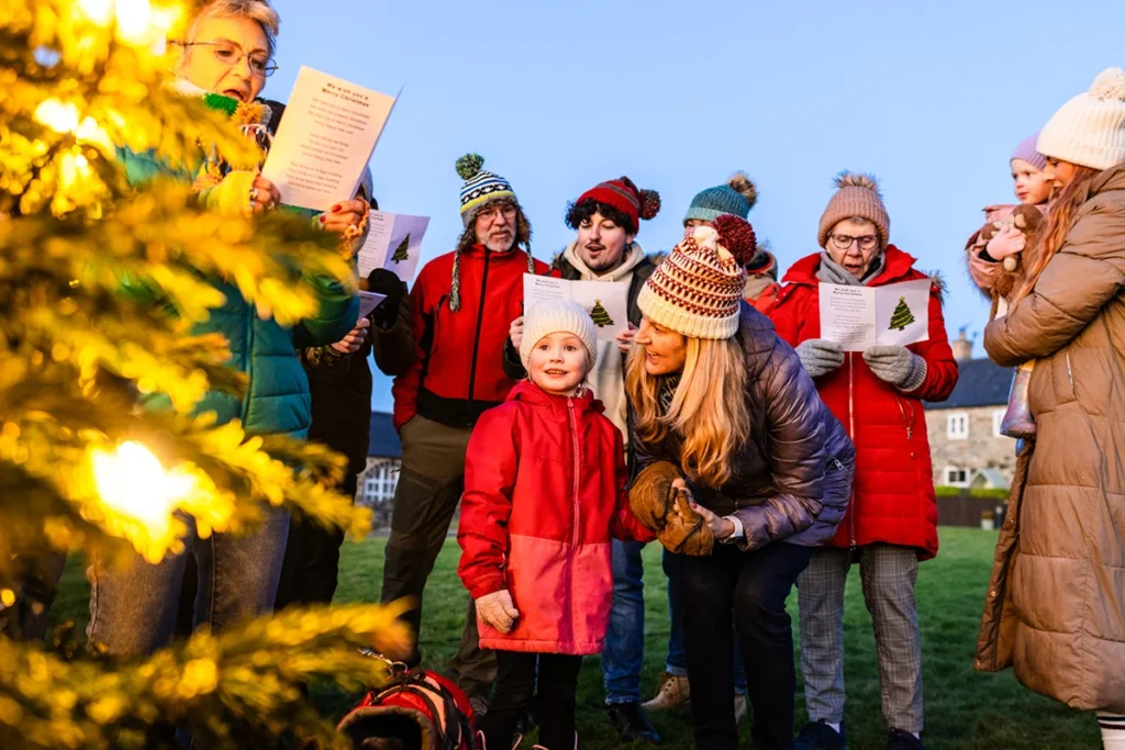 Eine Gruppe von Menschen ist zum weihnachtlichen Adventssingen um einen Weihnachtsbaum in Salzburg in Österreich versammelt