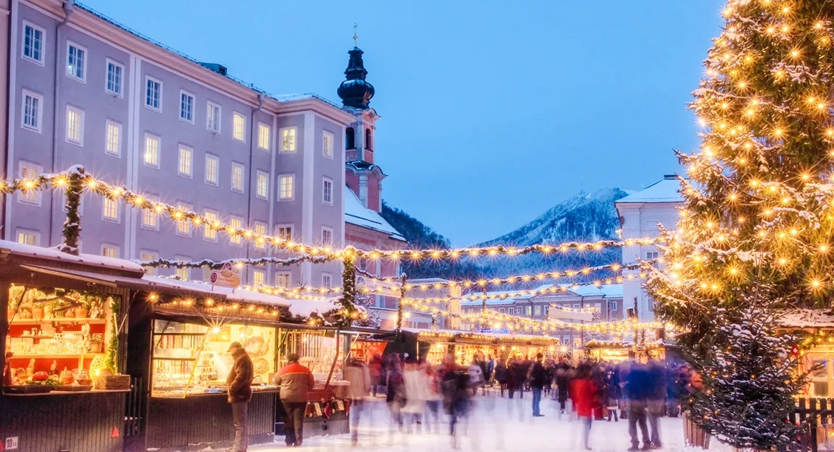 Der verschneite Weihnachtsmarkt in Salzburg in Österreich am Abend, mit leuchtender Weihnachtsbeleuchtung