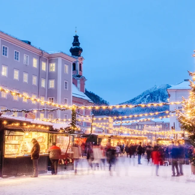 Der verschneite Weihnachtsmarkt in Salzburg in Österreich am Abend, mit leuchtender Weihnachtsbeleuchtung