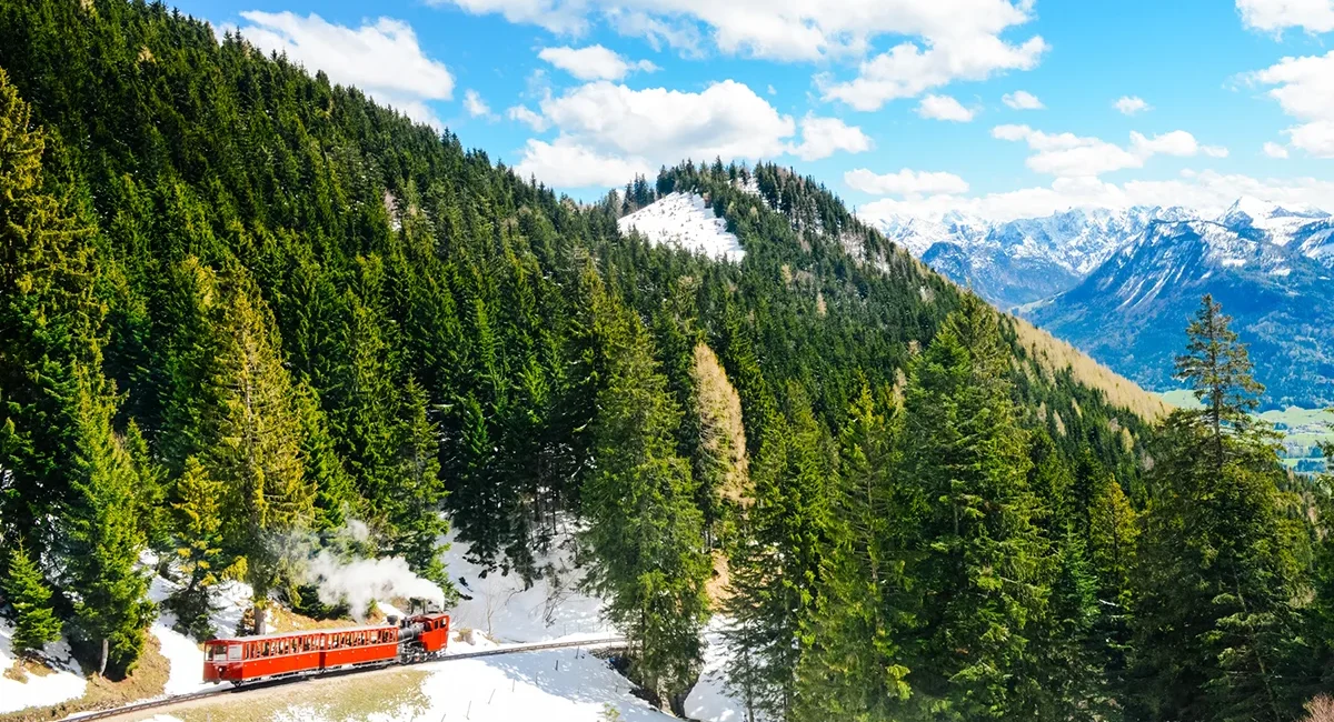 Die rote Schafbergbahn fährt durch eine winterliche Berglandschaft auf den Schafberg am Wolfangssee in Österreich