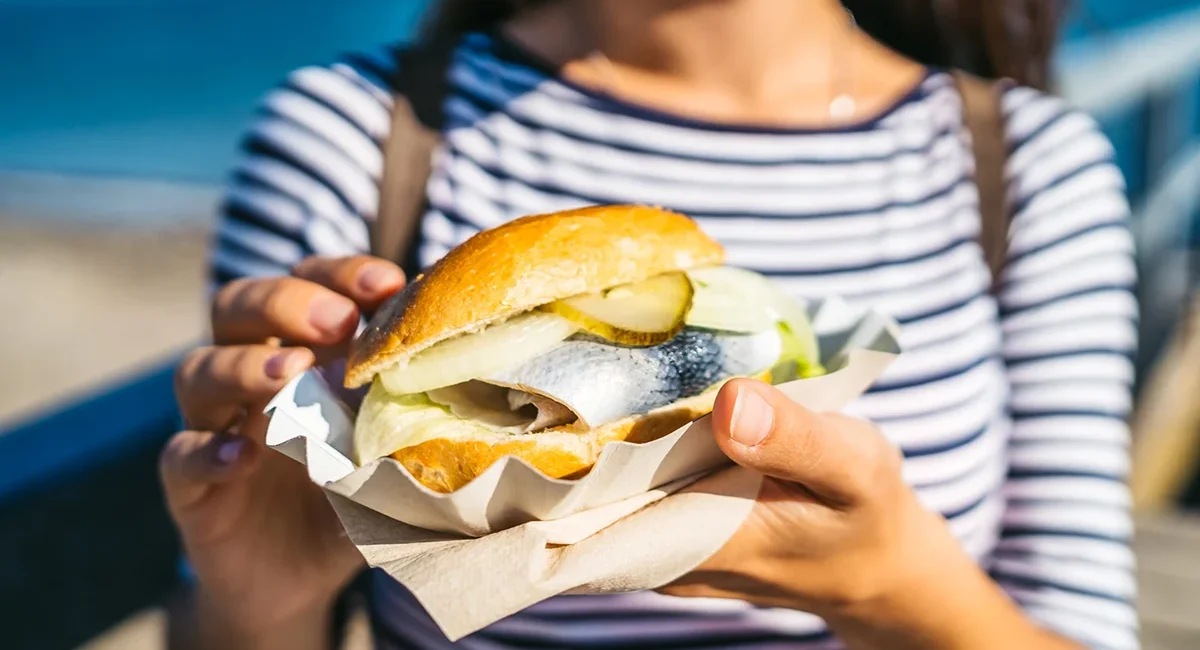 Frau hält ein Fischbrötchen in Schleswig-Holstein in der Hand