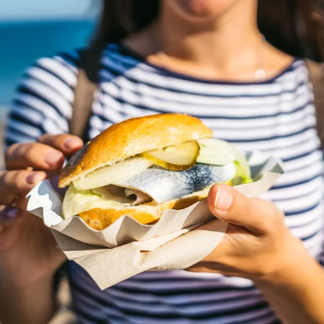 Frau hält ein Fischbrötchen in Schleswig-Holstein in der Hand