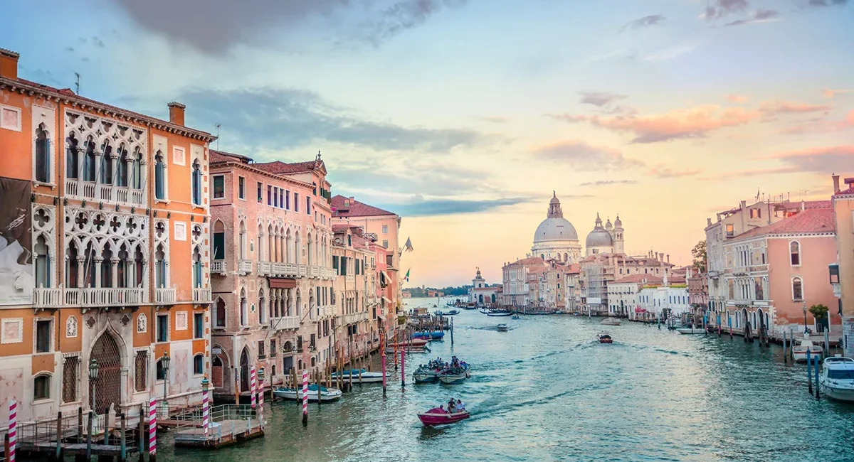 Blick in Venedig auf einen Kanal und einen Dom mit Kuppel am Wasser.