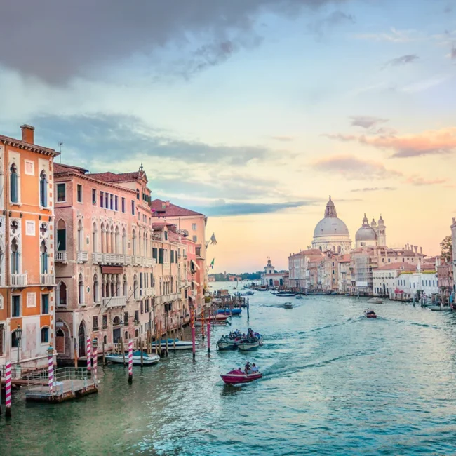 Blick in Venedig auf einen Kanal und einen Dom mit Kuppel am Wasser.