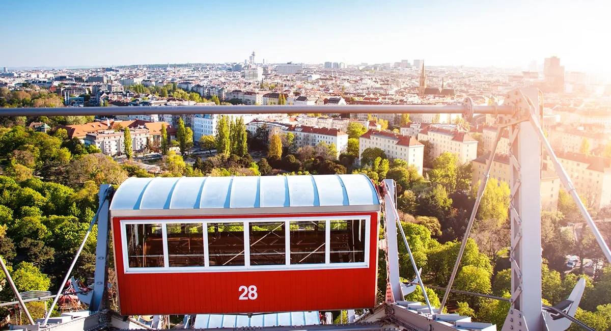 Ein roter Waggon des geschichtsträchtigen Wiener Riesenrads im Wiener Prater, von dem aus sich ein weiter Panoramablick über die sonnige Stadt Wien eröffnet.