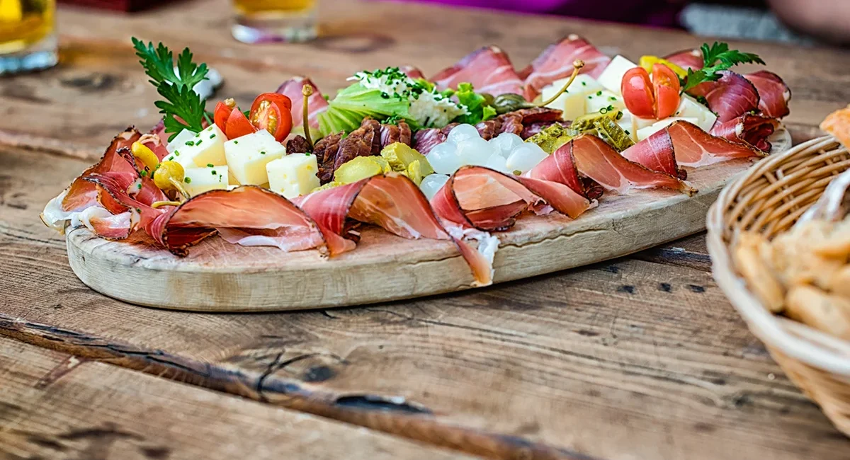 Eine österreichische Brettljause im Waldviertel mit Schinken, Käse und Gemüse auf einem rustikalen Tisch.