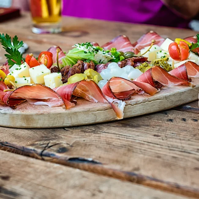 Eine österreichische Brettljause im Waldviertel mit Schinken, Käse und Gemüse auf einem rustikalen Tisch.